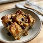 A close-up of a square slice of golden-brown apple butter bread pudding.