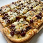 A close-up of the baked flatbread showing melted Gruyère and thyme garnish.