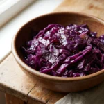 A serving bowl filled with vibrant purple braised cabbage with steam rising from it.