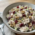 A scoop of cranberry chicken salad served on a piece of lettuce.